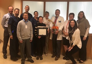 Donn Dexter,M.D., Neurology, (center, holding pail) accepts a physician excellence award from Mayo Clinic Health System’s organ donation team members (left to right) Richard Arndt, Damian Budzinski, Nick Waite, Wayne Street, Christine Burg, Patty Duerkop, Amy Williams, Dr. Dexter, Pam Johnson, Holly Thomas and Kelly Buchholtz. Dr. Dexter is the inaugural recipient of the University of Wisconsin Organ and Tissue Donation Award named in his honor.