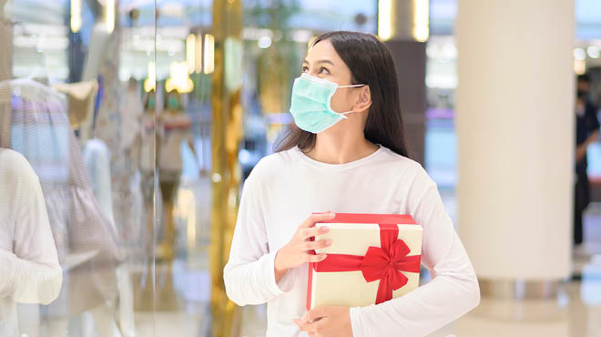 一名年轻女子戴着面具在假日购物